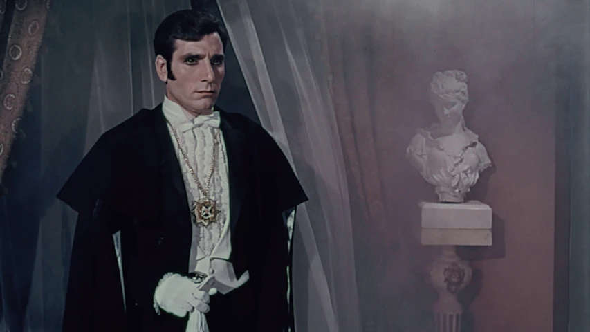 El actor Aldo Monti personificando al conde Drácula con esmoquin y capa elegante.